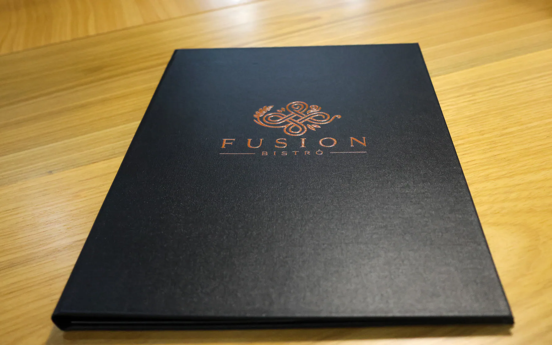 Ementa preta com o emblema do Fusion Bistrô em bronze